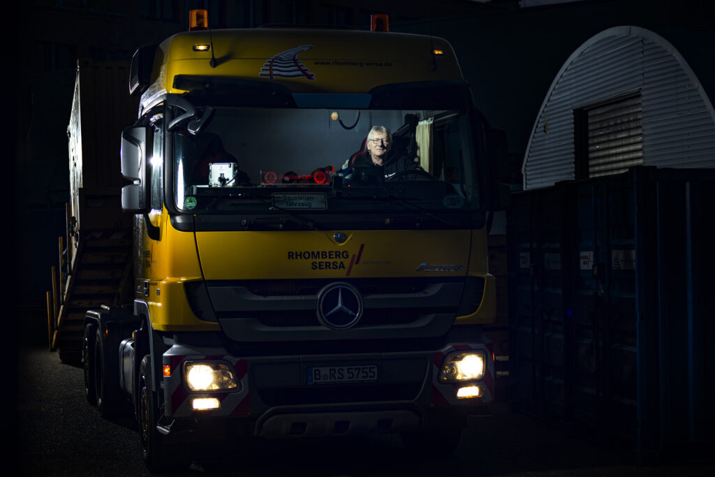 Frontansicht eines gelben Fahrzeugs in einer dunkel beleuchteten Werkhalle.