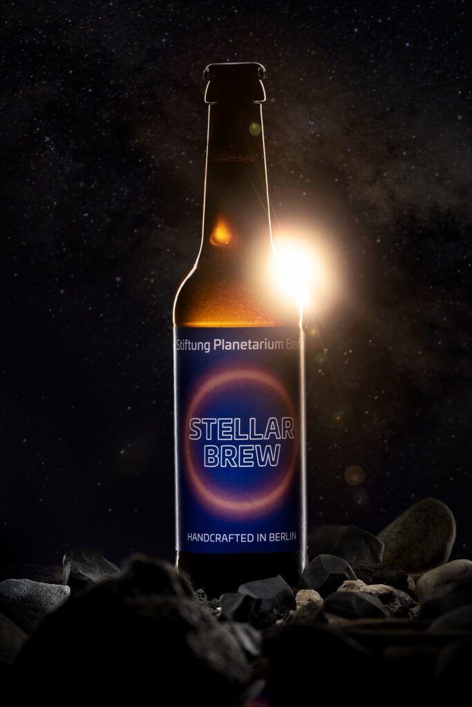 Eine Bierflasche mit blauem Etikett wird seitlich von hellem Gegenlicht umrandet.