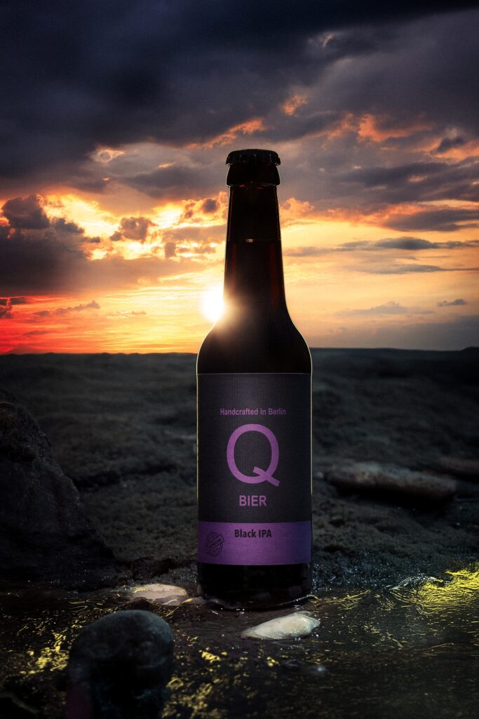 Eine Bierflasche steht als dunkle Silhouette vor einem orange leuchtenden Sonnenuntergang.