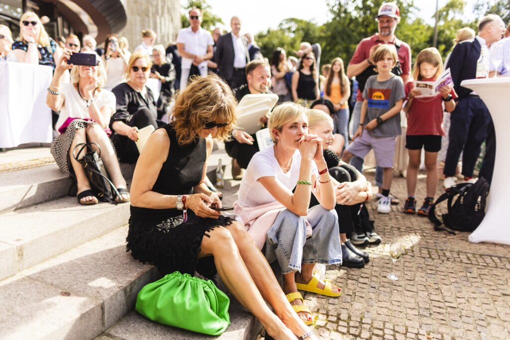 Gäste unterhalten sich an weiß gedeckten Tischen beim Sommerfest.